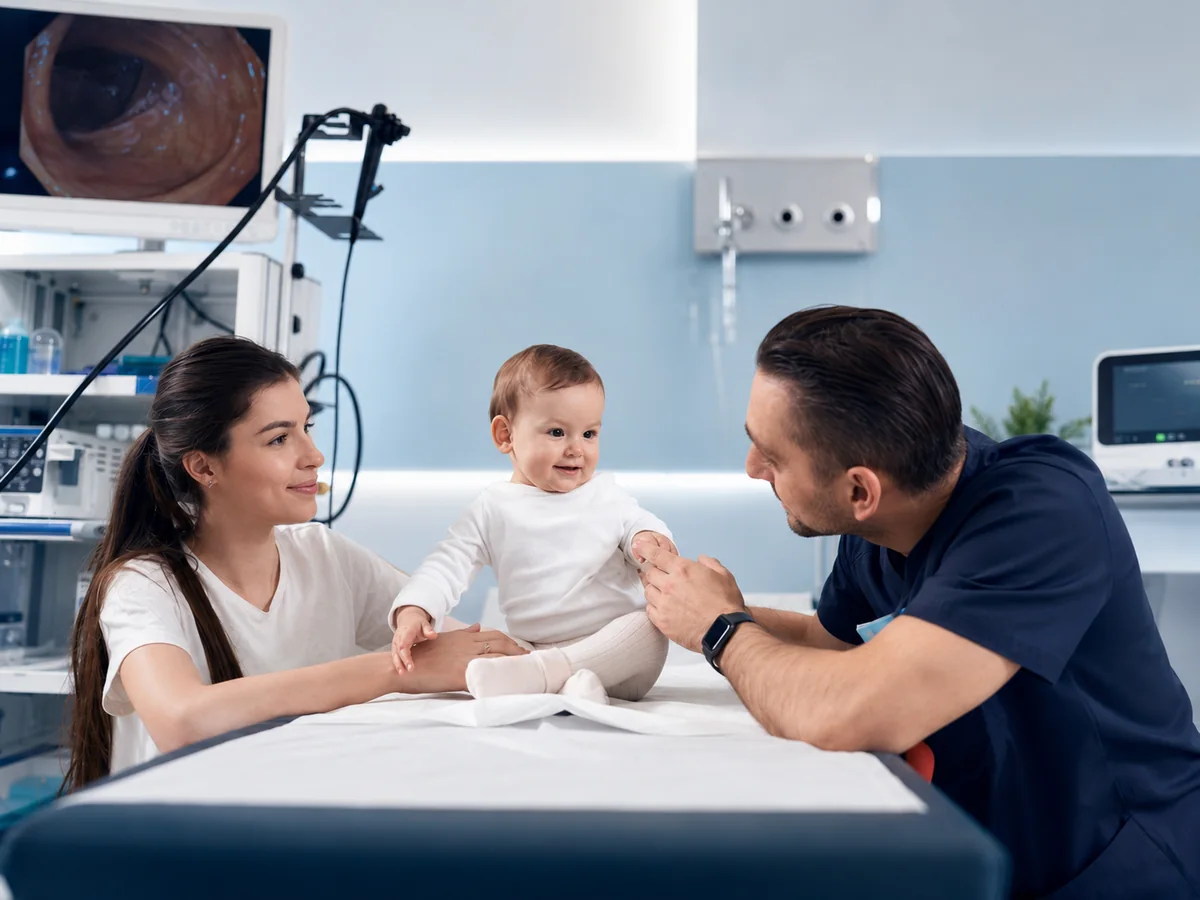 A clinician speaking with parents and their child in a clinical setting.
